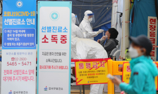 유치원과 초등학교 등교수업을 앞두고 서울 강서구의 한 미술학원 강사와 유치원생 1명이 신종 코로나바이러스 감염증(코로나19) 확진 판정을 받아 지역 내 감염증 확산 우려가 커지고 있는 25일 서울 강서구 보건소에서 관계자가 선별진료소를 찾은 시민의 검체를 채취하고 있다.   연합뉴스